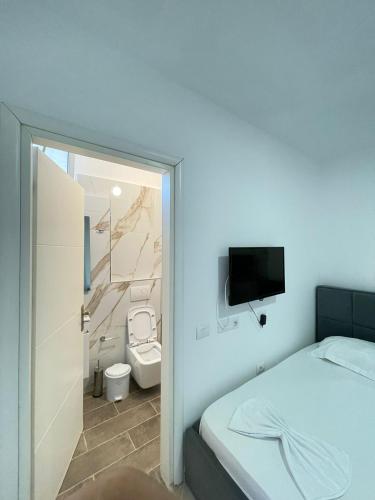 a bedroom with a bed and a bathroom with a toilet at Villa Besnik in Sarandë