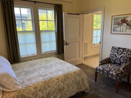 a bedroom with a bed and a chair and windows at SF Zen Center Guestrooms in San Francisco