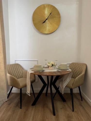 a dining room table with two chairs and a clock on the wall at Brits-Halley Luxury Apartments in Annfield Plain