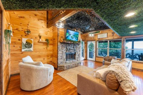 a living room with a couch and a stone fireplace at Big Time Hill Cabin with an indoor pool hot tub & great views in Bryant