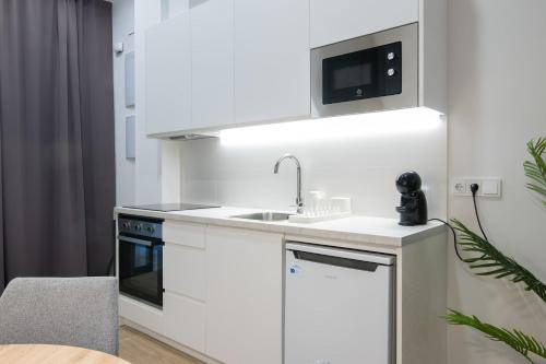 a white kitchen with a sink and a microwave at Luxury Apartment Oceanografic 9 in Valencia