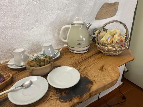 a wooden table with white plates and a tea kettle at La casa dei mestieri in Lanusei