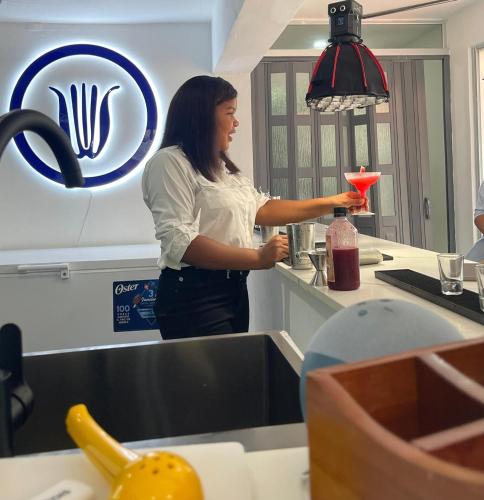 a woman standing in a kitchen holding a drink at Hotel Neptuno Refugio in Boca Chica