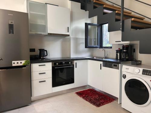 a kitchen with white cabinets and a washer and dryer at Nuovo Maistros Villas in Tsoukaladhes