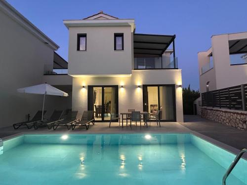 a villa with a swimming pool in front of a house at Nuovo Maistros Villas in Tsoukaladhes