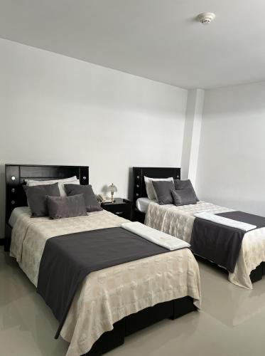 two beds sitting next to each other in a room at Hotel El Potrillo in Puerto López