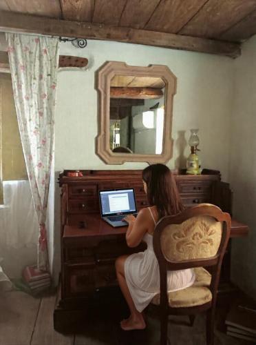 a woman sitting in a chair using a laptop computer at S'Antiga Inn, centro storico ed escursionismo in Sardegna in Seùlo