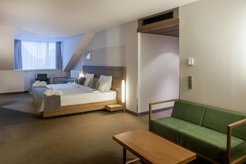 a bedroom with a bed and a green couch at Hotel Stadtpalais in Cologne