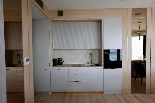 a kitchen with white cabinets and a sink at Luksusowy apartament Infinity Chill Baltic Spa in Międzyzdroje