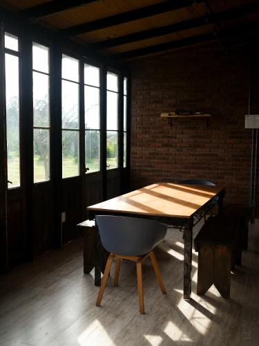a wooden table in a room with windows at Caliu Earthship Ecolodge in Colonia del Sacramento