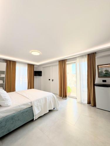 a white bedroom with a bed and a television at Casa di Giò in Ksamil
