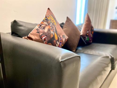 a person laying on a couch with pillows at APARTMENTS GH - Accra - Cantonments - Embassy Gardens in Accra