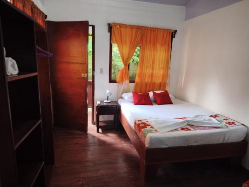 a bedroom with a bed with red pillows and a window at Cabañas Daneysha in Tortuguero