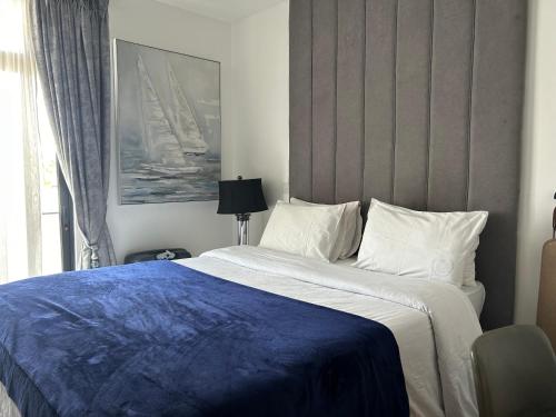 a bedroom with a large bed with a blue blanket at APARTMENTS GH - Accra - Cantonments - Embassy Gardens in Accra