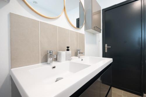 un bagno con un lavandino bianco e uno specchio di La Villa des Oliviers - Les Demeures d 'Adrien a Valenciennes