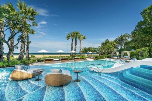 a pool at a resort with chairs and tables at Pattaya Marriott Resort and Spa in Jomtien Beach