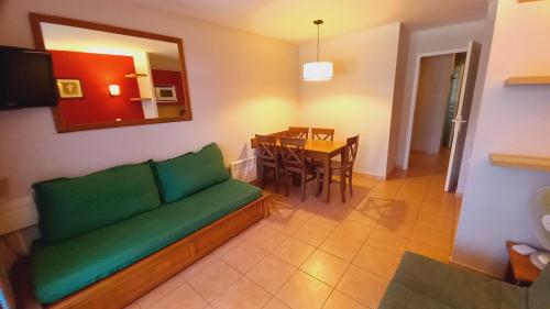 un salon avec un canapé vert et une table dans l'établissement Maison avec piscine chauffée en résidence, 5 pers, RDC, lac et nature, à Monflanquin