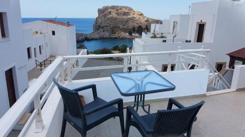 a balcony with chairs and a table and the ocean at Lindos Panorama in Líndos