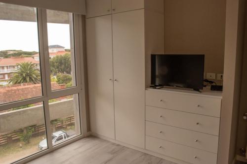 a bedroom with a dresser with a tv and a window at Departamento edificio Arenas IV in Ostende