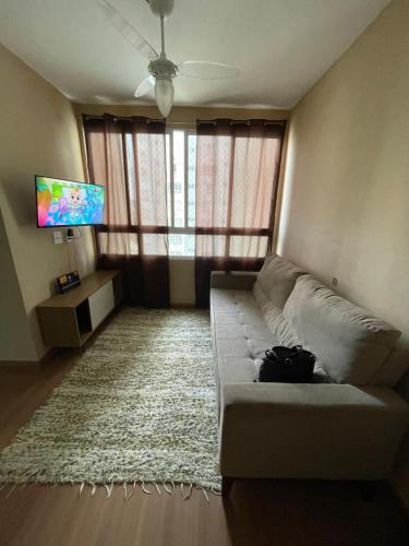 Una sala de estar con un sofá y un televisor de pantalla plana. en Apto 2 qts em Xerém próximo ao CT do Fluminense, en Duque de Caxias