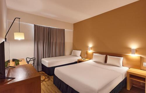 a hotel room with two beds and a television at Hotel Nacional Inn Bauru in Bauru