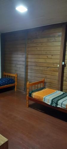 two beds in a room with a wooden wall at Casa do canto das ondas in Bombinhas