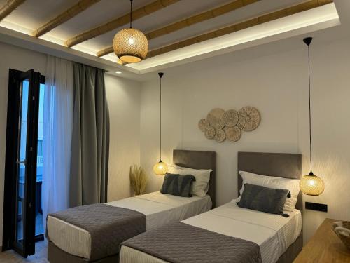 two beds in a hotel room with two lamps at Olive Garden Hotel in Agios Prokopios