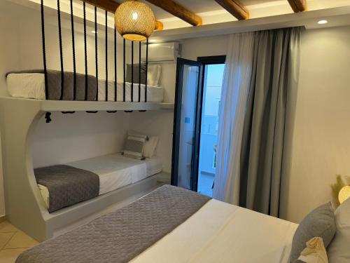 a bedroom with two beds and a window with a balcony at Olive Garden Hotel in Agios Prokopios