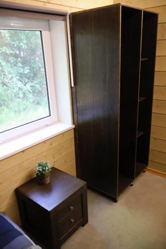 a bedroom with a black cabinet and a table and a window at Vertikāles Austrumi in Cenkone