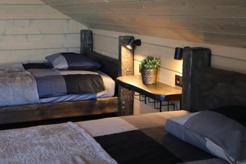 a bedroom with two beds and a table with a night stand at Vertikāles Austrumi in Cenkone