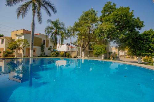 a large blue swimming pool with palm trees and houses at New Bamboo Casa Calma in Emiliano Zapata