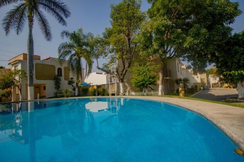 a large blue swimming pool with trees and houses at New Bamboo Casa Calma in Emiliano Zapata