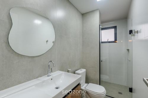 a bathroom with a sink and a toilet and a mirror at Prédio c/ Aptos Novos a 300m da Praia - EEP in Guarapari