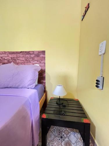 a bedroom with a bed and a table with a lamp at Pousada Morango das Palmas in Praia de Palmas