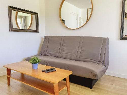 a couch in a living room with a table and a mirror at Résidence grand jardin attenant tennis, mini golf, sauna, pétanque in Cucq