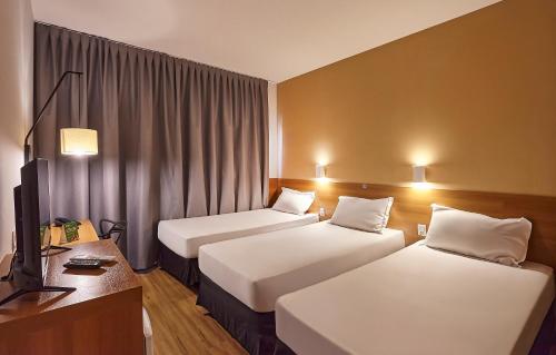 a hotel room with two beds and a television at Hotel Nacional Inn Bauru in Bauru