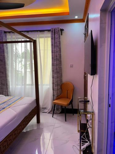 a bedroom with a bed and a tv and a chair at Pearl Studio in Mombasa