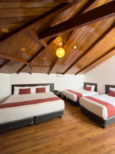two beds in a room with wooden ceilings at Hotel San Pedro Plaza in Cusco
