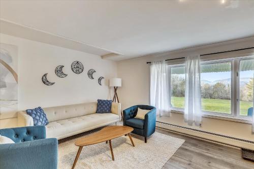 a living room with a couch and chairs and windows at Lang Farm Mountain View in Stowe