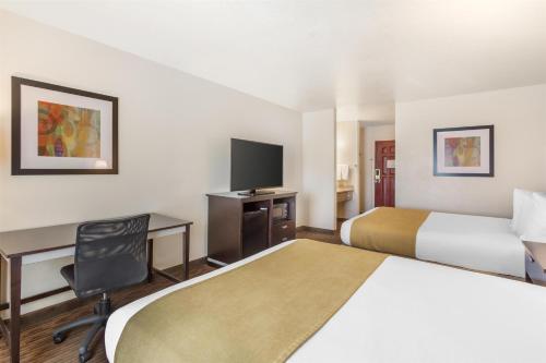 a hotel room with two beds and a desk and a tv at Best Western Luxury Inn in Tracy
