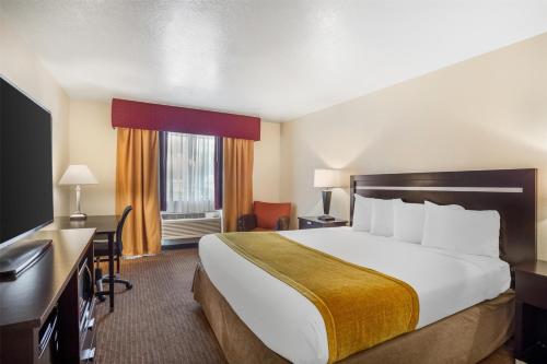 a hotel room with a large bed and a desk at Best Western Luxury Inn in Tracy