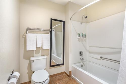 a bathroom with a white toilet and a bath tub at Best Western Luxury Inn in Tracy