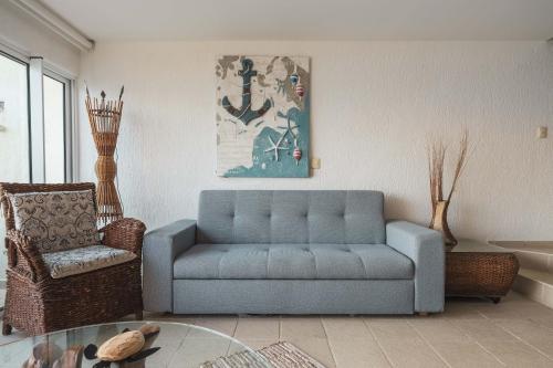 a living room with a blue couch and a chair at Maravilloso departamento frente al mar, Acapulco in Acapulco