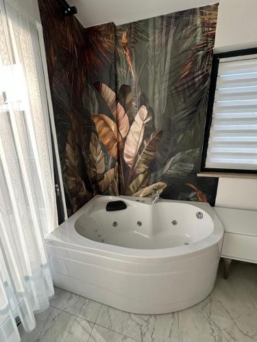 a bath tub in a bathroom with a tropical wallpaper at VILLA KoSAR in Eskiömerler