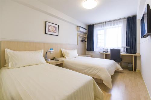 a hotel room with two beds and a window at Jinjiang Inn Wuxi Meicun in Wuxi