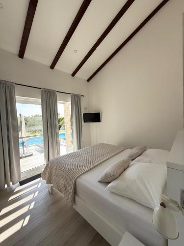 a white bedroom with a bed and a large window at Luxury villa near Šibenik with heated pool, jacuzzi & sauna in Šibenik