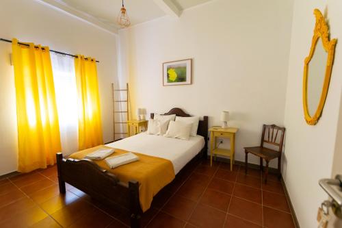 a bedroom with a bed with yellow curtains and a chair at Natur - Quinta Nª Srª da Conceição - T4 - Golegã in Golegã
