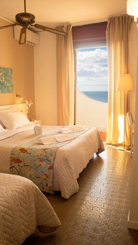 a hotel room with two beds and a large window at Hotel Sinuessa Terme in Mondragone