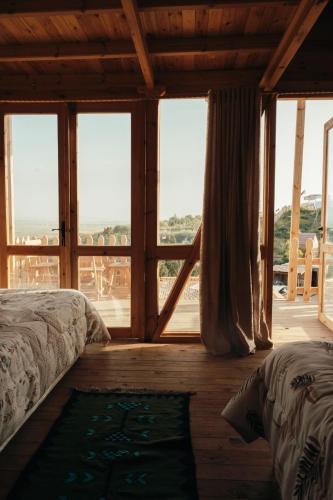 a bedroom with a bed and a large window at Ghar El Melh Outdoors in Raʼs al Jabal