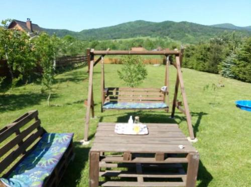 a wooden picnic table and bench in a field at Mała Chatka w Dolinie Niedźwiadka - Drewniany Biały Domek in Wysowa-Zdrój
